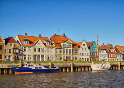 Buildings by river against clear sky