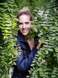 Portrait of young woman standing amidst plants