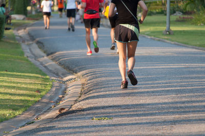 Rear view of woman jogging on road at park