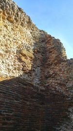 Low angle view of rock on cliff against sky