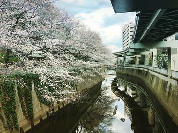 Footbridge over canal in city against sky