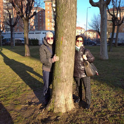 Portrait of young man standing by tree trunk