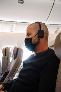 Man seating in the airplane wearing a mask