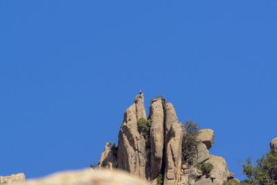 Low angle view of rock formation against clear blue sky