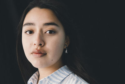 Portrait of teenage girl against black background