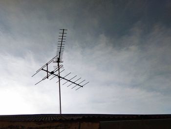 Low angle view of communications tower against cloudy sky