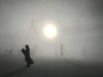 Silhouette man standing on street during foggy weather