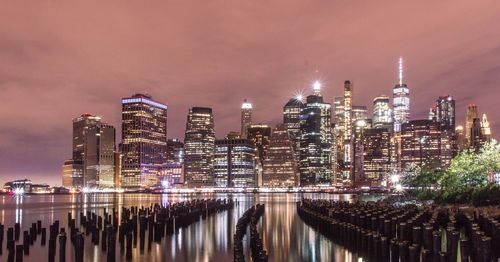 Illuminated modern buildings against sky at night