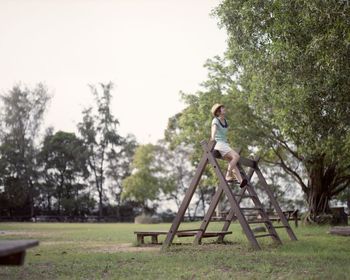 Woman sitting on wooden play equipment at playground