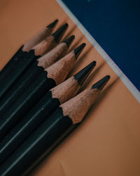 Macro shot of black pencils with a mix of orange and blue background.