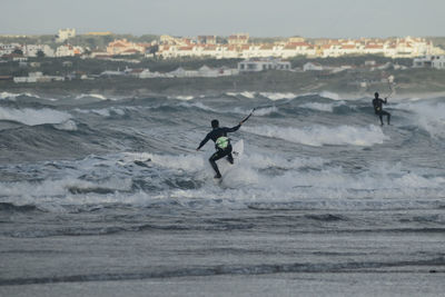 Man surfing in sea against sky during sunset