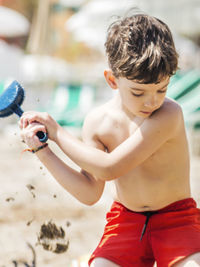 Rear view of shirtless boy playing in water