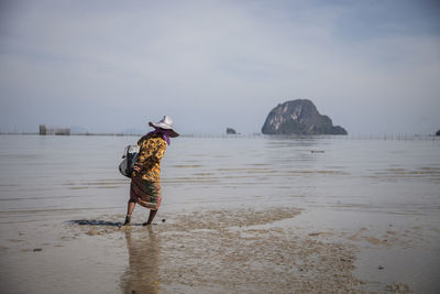 Woman collecting oysters on beach