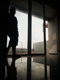 Silhouette man standing by window in building