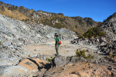 Rear view of man on standing on field against rock mountains