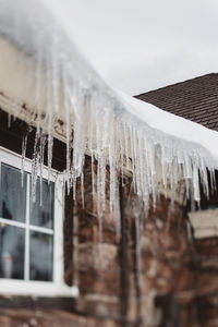 Close-up of icicles on roof against sky during winter