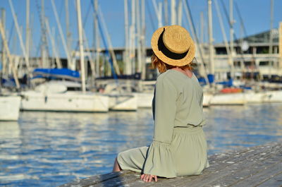 Rear view of woman sitting at harbor