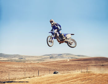 Man riding bicycle on field against sky