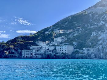 Buildings by sea against blue sky