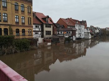 Buildings by canal against sky