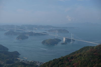 Suspension bridge over sea against sky