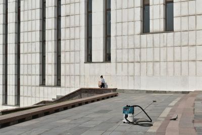 Rear view of man walking on footpath against building