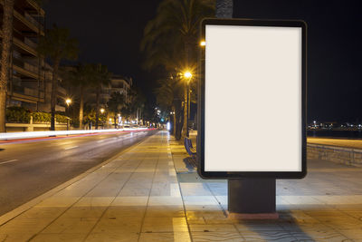 Illuminated street lights on road in city at night