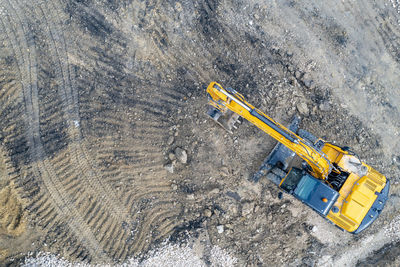 Aerial view of the stopped yellow excavator at a construction site