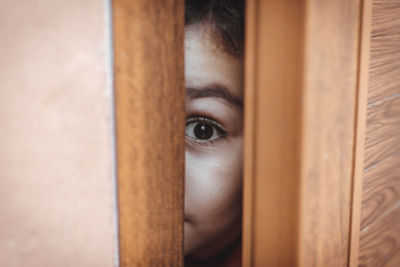 Close-up portrait of boy peeking from door