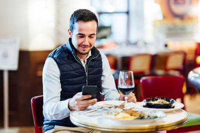 Mid adult man using smart phone in restaurant