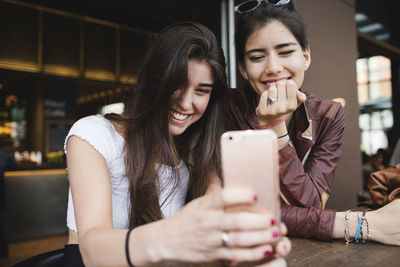 Two happy young women looking at cell phone in a bar