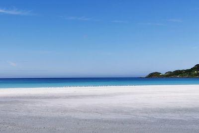 Scenic view of beach against blue sky