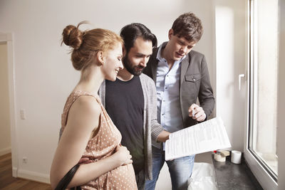 Real estate agent showing expecting parents a contract in a new apartment