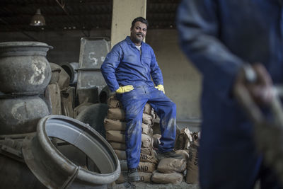 Man having a break sitting on sacks in industrial pot factory