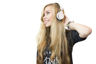 Smiling young woman listening music against white background
