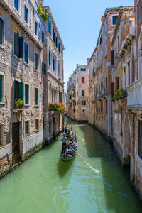 People in canal amidst buildings