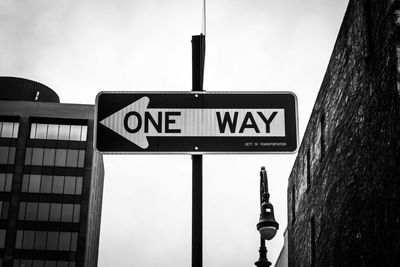 Low angle view of arrow sign against the sky