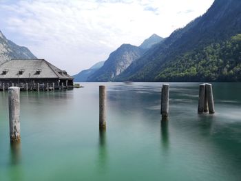 Wooden posts in lake against sky