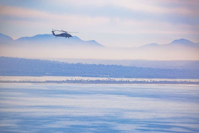 Helicopter flying over sea against sky