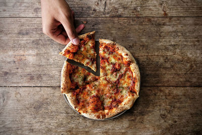 Directly above shot of hand holding pizza on table