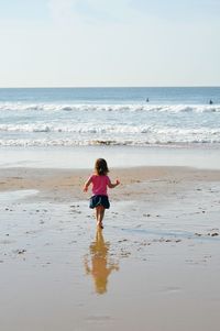 Rear view of boy on beach against sky