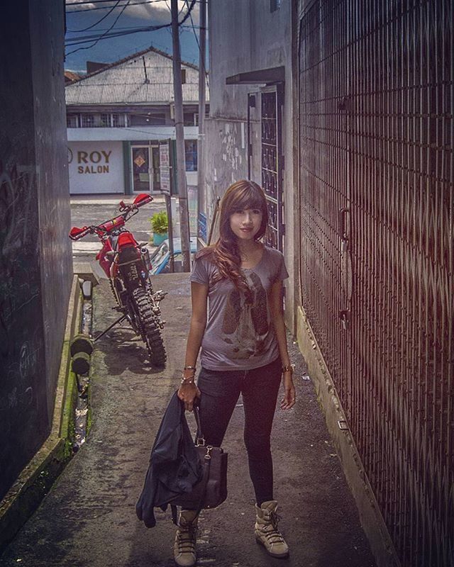 full length, lifestyles, building exterior, casual clothing, young women, built structure, architecture, young adult, leisure activity, standing, street, person, front view, graffiti, three quarter length, walking, long hair, outdoors