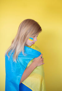 Side view of young woman against yellow background