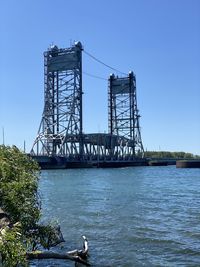 Bridge over river against clear blue sky