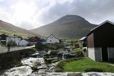 Scenic view of residential buildings by mountains against sky