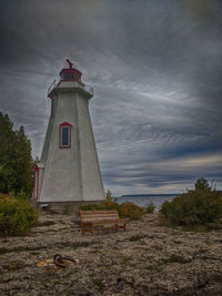 Lighthouse by building against sky