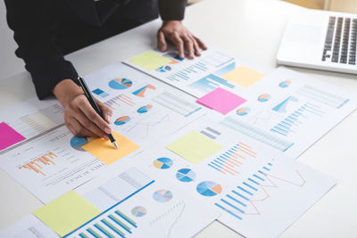 Midsection of businesswoman analyzing data on desk in office