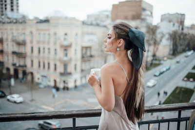 Side view of young woman drinking railing