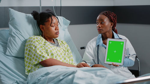 Doctor showing digital tablet to patient at clinic