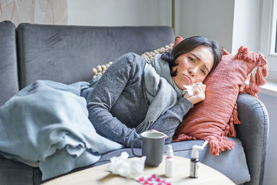 Young woman using phone while sitting on sofa at home